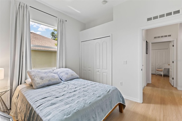 bedroom featuring visible vents, baseboards, light wood finished floors, and a closet