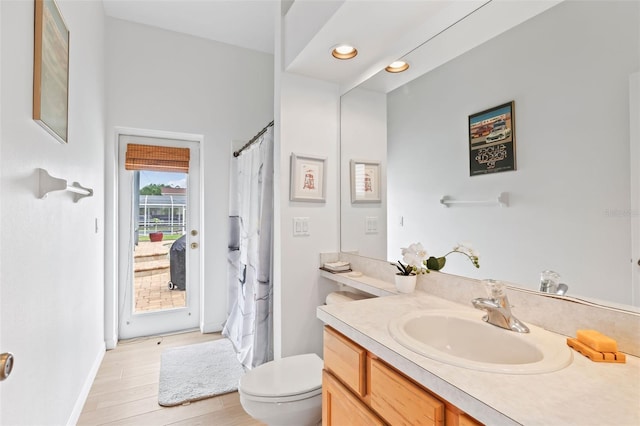 bathroom with vanity, curtained shower, toilet, baseboards, and wood finished floors