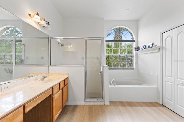 full bathroom featuring wood finished floors, a shower stall, a bath, and vanity