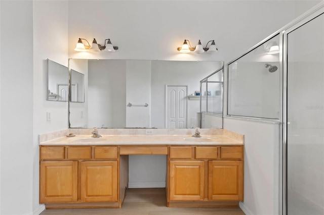 full bath featuring double vanity, wood finished floors, a stall shower, and a sink