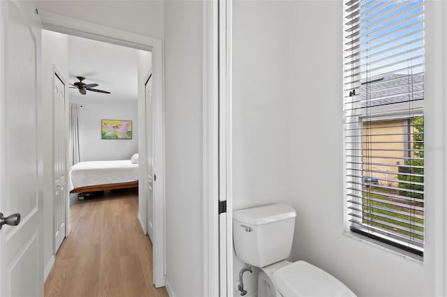 ensuite bathroom with ceiling fan, wood finished floors, toilet, and ensuite bath