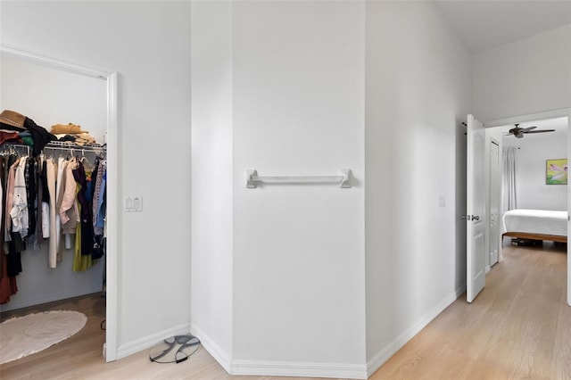 interior space with wood finished floors, baseboards, a ceiling fan, and a walk in closet