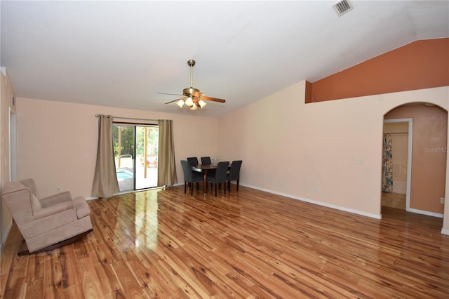 living area with ceiling fan, light wood finished floors, arched walkways, lofted ceiling, and visible vents