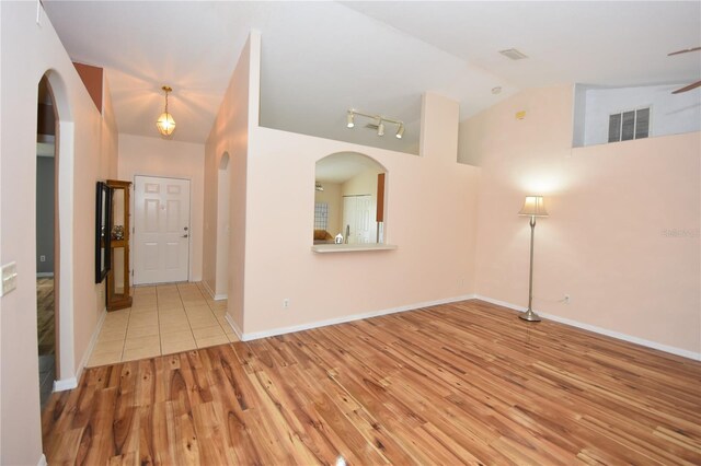 interior space featuring arched walkways, visible vents, wood finished floors, and lofted ceiling