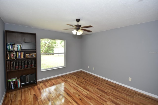spare room with baseboards, ceiling fan, and wood finished floors