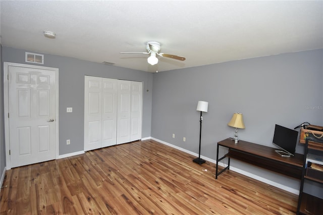 office space featuring visible vents, a ceiling fan, baseboards, and wood finished floors