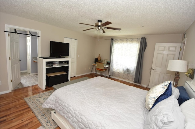 bedroom featuring a textured ceiling, visible vents, and wood finished floors