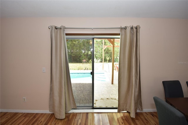 doorway to outside with baseboards and wood finished floors