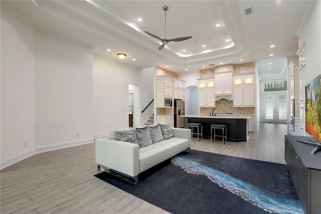 45 King Palm Ct, Ponte Vedra, FL 32081 - living area with ornamental molding, a ceiling fan, a tray ceiling, light wood-type flooring, and arched walkways