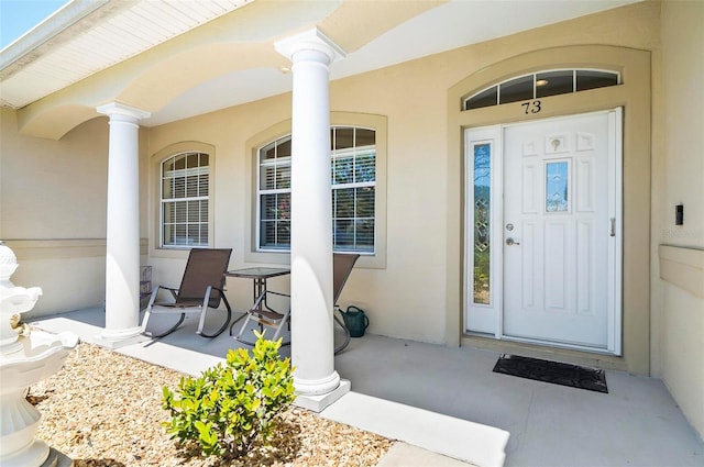 property entrance with stucco siding and a porch