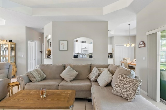 living room with an inviting chandelier, light tile patterned floors, and a tray ceiling