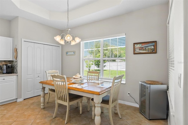 dining area with baseboards, a tray ceiling, light tile patterned flooring, and a notable chandelier