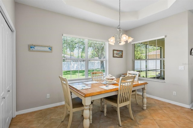 dining area with baseboards, a raised ceiling, light tile patterned flooring, and a notable chandelier
