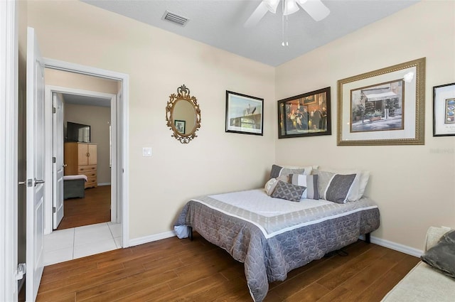 bedroom featuring visible vents, baseboards, ceiling fan, and wood finished floors