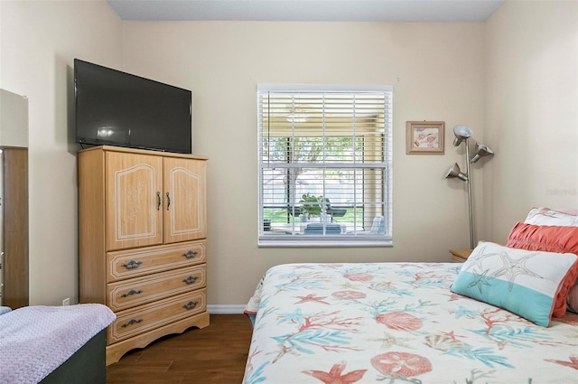 bedroom with baseboards and dark wood-type flooring