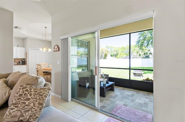 entryway featuring light tile patterned floors, baseboards, a notable chandelier, and visible vents