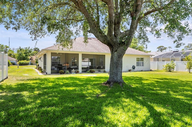back of property featuring a lawn, fence, stucco siding, and a sunroom