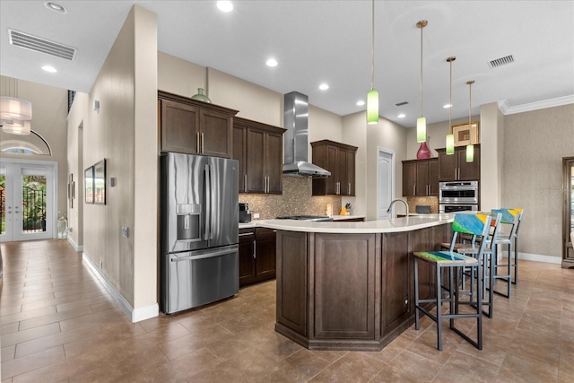 kitchen with appliances with stainless steel finishes, visible vents, light countertops, dark brown cabinets, and wall chimney exhaust hood