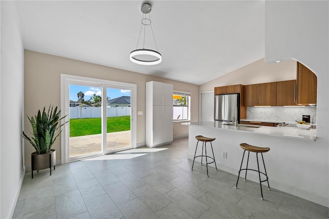 77 Freeport Ln, Palm Coast, FL 32137 - kitchen featuring brown cabinets, freestanding refrigerator, a peninsula, backsplash, and healthy amount of natural light