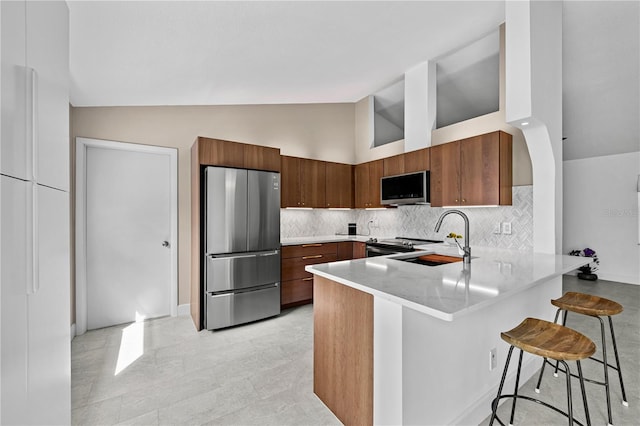 77 Freeport Ln, Palm Coast, FL 32137 - kitchen with appliances with stainless steel finishes, a peninsula, light countertops, decorative backsplash, and a breakfast bar area