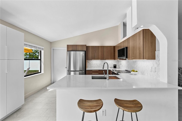 77 Freeport Ln, Palm Coast, FL 32137 - kitchen with stainless steel appliances, a peninsula, vaulted ceiling, modern cabinets, and tasteful backsplash