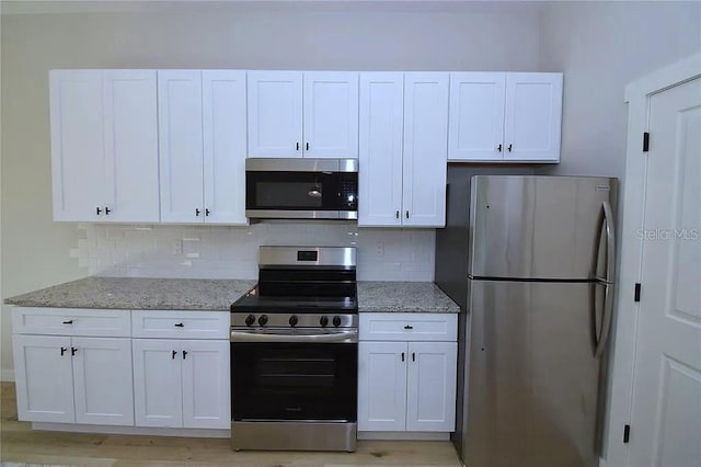 1 Fanshawe Ln, Palm Coast, FL 32137 - kitchen featuring white cabinetry, light stone countertops, appliances with stainless steel finishes, and decorative backsplash