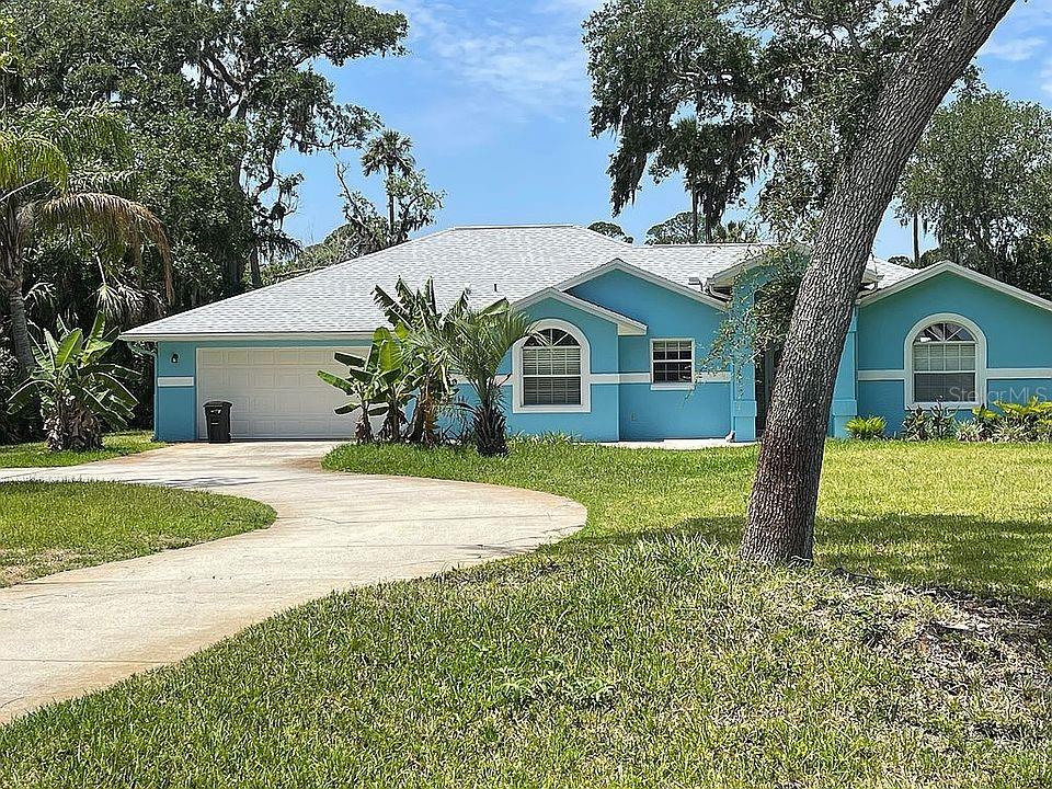 ranch-style home with concrete driveway, stucco siding, an attached garage, and a front yard