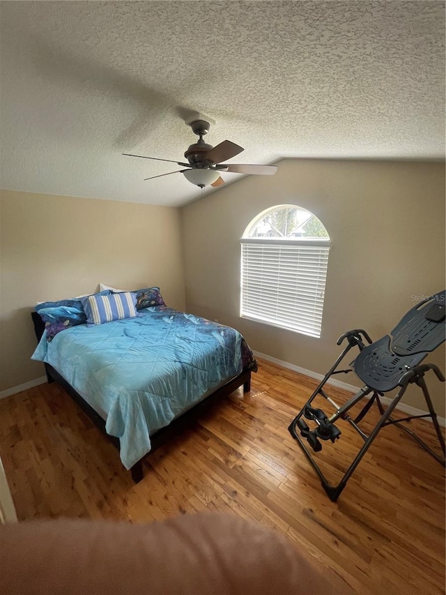 1501 Lambert Ave, Flagler Beach, FL 32136 - bedroom with wood finished floors, vaulted ceiling, a textured ceiling, baseboards, and a ceiling fan