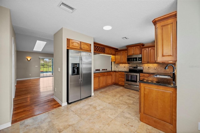 1501 Lambert Ave, Flagler Beach, FL 32136 - kitchen with appliances with stainless steel finishes, a skylight, decorative backsplash, and brown cabinets