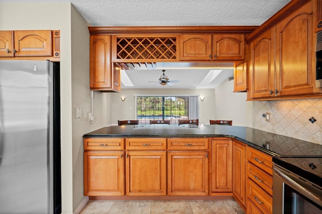 1501 Lambert Ave, Flagler Beach, FL 32136 - kitchen with stainless steel appliances, a peninsula, brown cabinetry, ceiling fan, and decorative backsplash