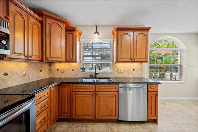 1501 Lambert Ave, Flagler Beach, FL 32136 - kitchen featuring stainless steel appliances, brown cabinetry, a textured ceiling, tasteful backsplash, and dark stone countertops
