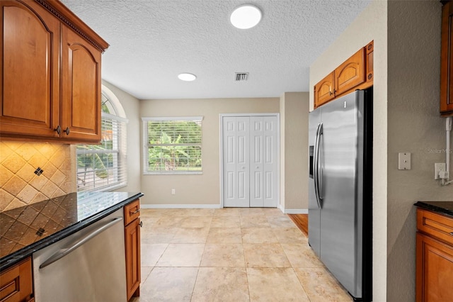 1501 Lambert Ave, Flagler Beach, FL 32136 - kitchen featuring stainless steel appliances, dark countertops, decorative backsplash, brown cabinetry, and light tile patterned floors