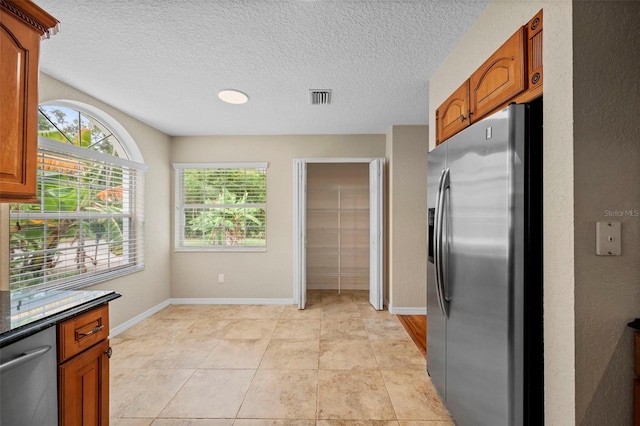 1501 Lambert Ave, Flagler Beach, FL 32136 - kitchen featuring stainless steel appliances, brown cabinetry, dark countertops, and a textured ceiling