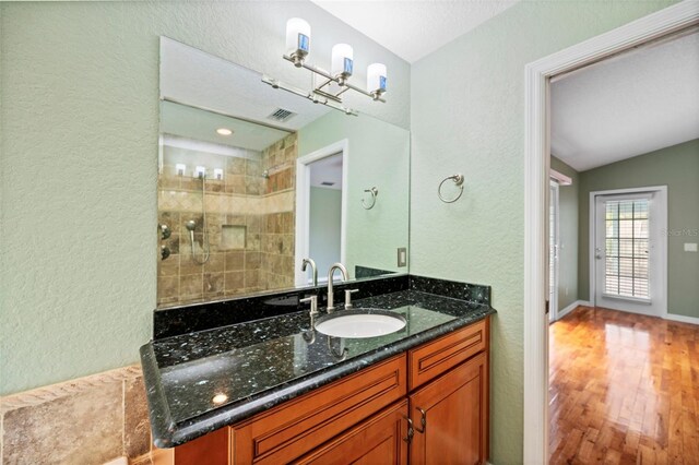 1501 Lambert Ave, Flagler Beach, FL 32136 - full bath with vanity, a textured wall, wood finished floors, vaulted ceiling, and tiled shower