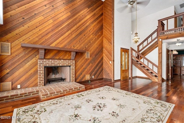 unfurnished living room with stairway, baseboards, ceiling fan, and a towering ceiling