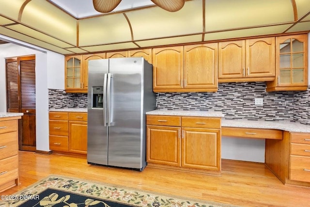 kitchen with glass insert cabinets, decorative backsplash, stainless steel refrigerator with ice dispenser, light countertops, and light wood-style floors