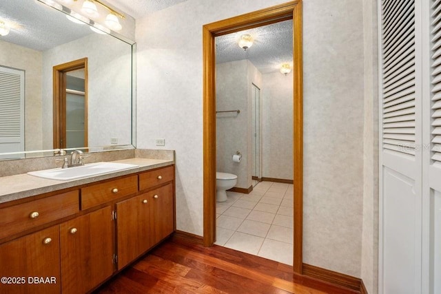 bathroom with a textured ceiling, wood finished floors, and a closet