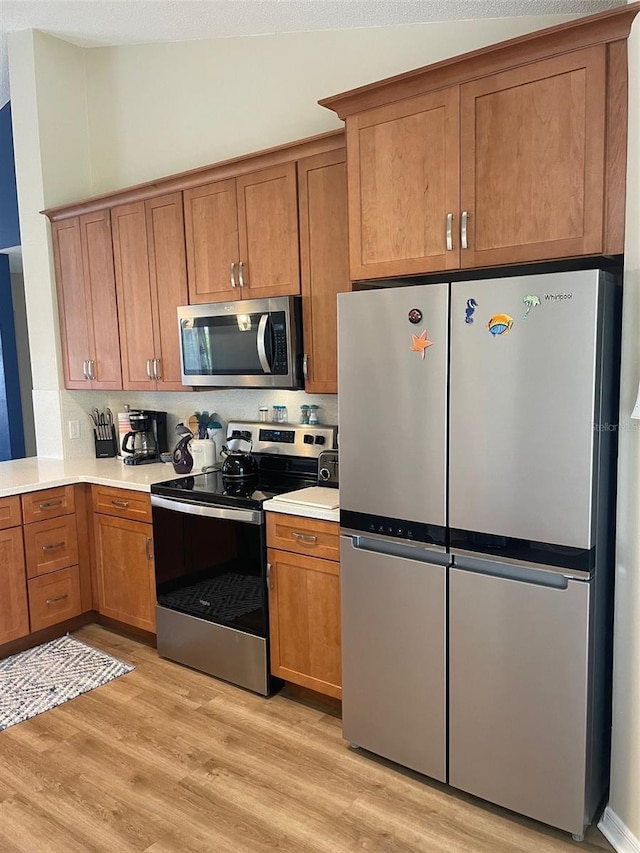 161 Bayside Dr, Palm Coast, FL 32137 - kitchen with stainless steel appliances, light wood-style flooring, brown cabinetry, light countertops, and lofted ceiling