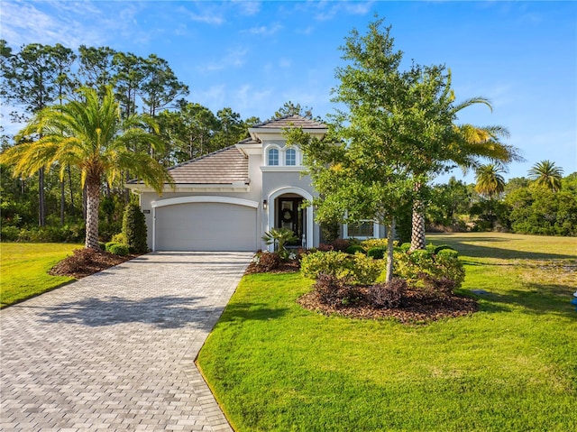 628 Mahogany Run, Palm Coast, FL 32137 - mediterranean / spanish-style home with a front lawn, a garage, decorative driveway, a tiled roof, and stucco siding