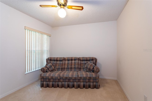 living area with a textured ceiling, a ceiling fan, carpet floors, and baseboards