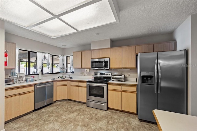 kitchen featuring light floors, light brown cabinets, appliances with stainless steel finishes, light countertops, and a textured ceiling