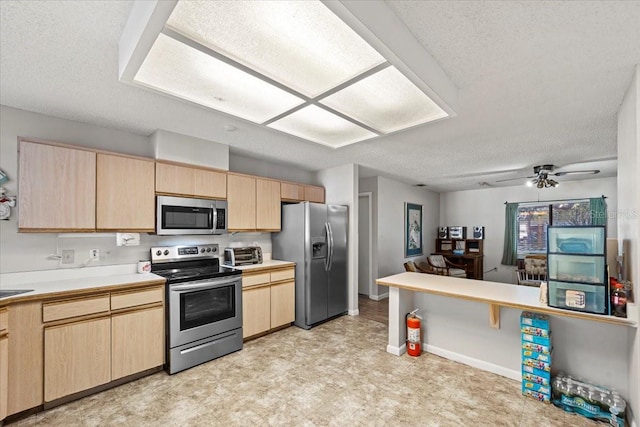 kitchen featuring light countertops, a textured ceiling, stainless steel appliances, and light brown cabinets