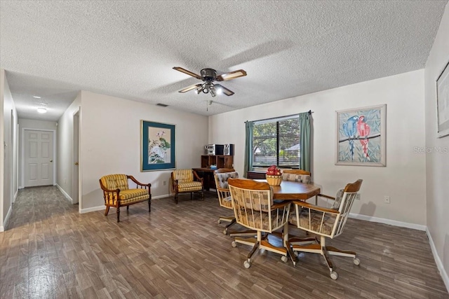 dining space with a textured ceiling, ceiling fan, wood finished floors, and baseboards