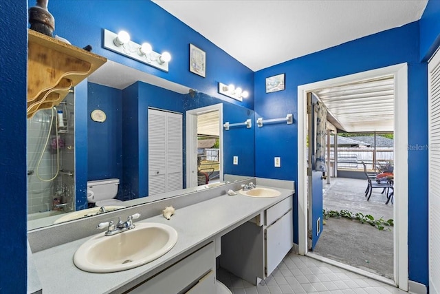 full bath featuring toilet, double vanity, a sink, and tile patterned floors