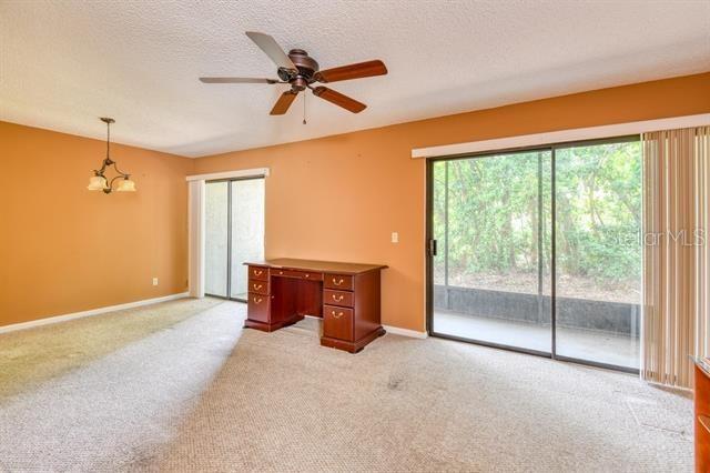 27 Catalonia Ct Unit A, Saint Augustine, FL 32086 - unfurnished room featuring a textured ceiling, baseboards, light colored carpet, and ceiling fan with notable chandelier
