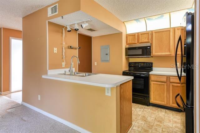 27 Catalonia Ct Unit A, Saint Augustine, FL 32086 - kitchen featuring visible vents, a textured ceiling, rail lighting, a sink, and black appliances