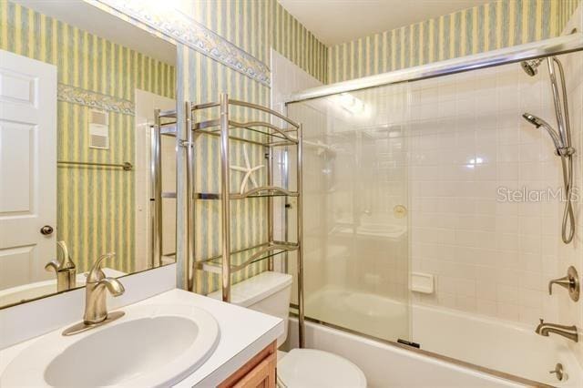27 Catalonia Ct Unit A, Saint Augustine, FL 32086 - bathroom featuring toilet, wallpapered walls, shower / bath combination with glass door, and vanity
