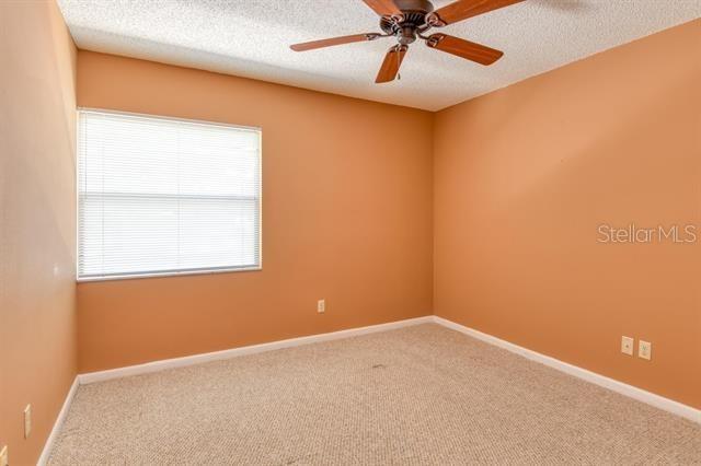 27 Catalonia Ct Unit A, Saint Augustine, FL 32086 - carpeted empty room with baseboards, a textured ceiling, and ceiling fan