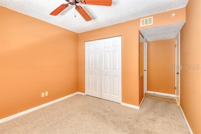 27 Catalonia Ct Unit A, Saint Augustine, FL 32086 - unfurnished bedroom featuring a textured ceiling, visible vents, carpet, and a closet