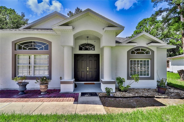 entrance to property with roof with shingles and stucco siding